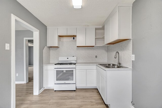 kitchen with sink, white range with gas cooktop, white cabinets, and light hardwood / wood-style floors