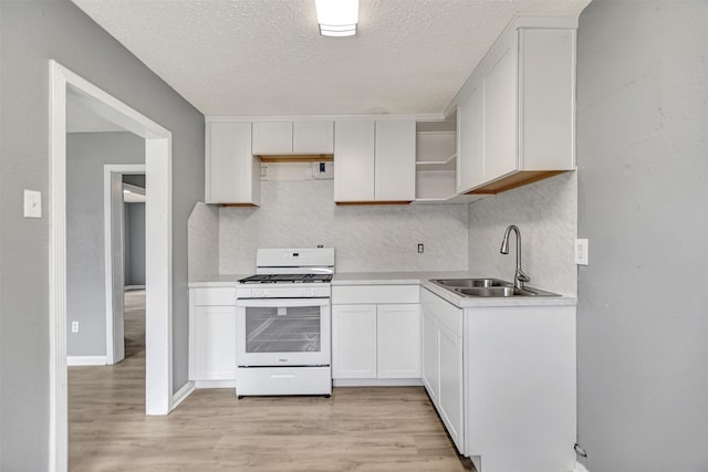 kitchen with white cabinetry, light hardwood / wood-style flooring, gas range gas stove, sink, and decorative backsplash