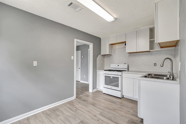 kitchen with a textured ceiling, white range with gas cooktop, white cabinets, sink, and light hardwood / wood-style flooring