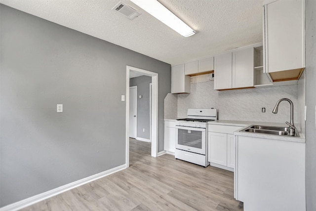 kitchen featuring white gas range, light hardwood / wood-style flooring, sink, a textured ceiling, and white cabinets