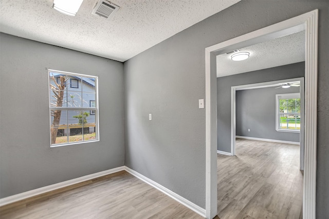 empty room featuring ceiling fan, light hardwood / wood-style floors, and a textured ceiling