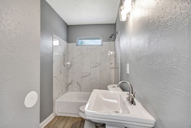 bathroom with sink, wood-type flooring, a textured ceiling, and tiled shower / bath