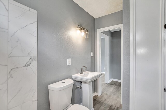 bathroom featuring wood-type flooring, a textured ceiling, and toilet