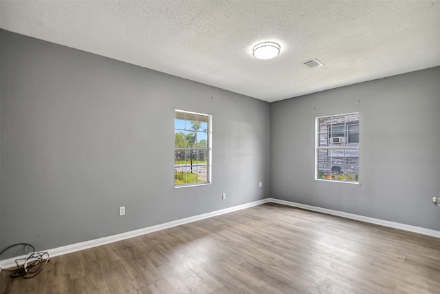 empty room with a textured ceiling and wood-type flooring