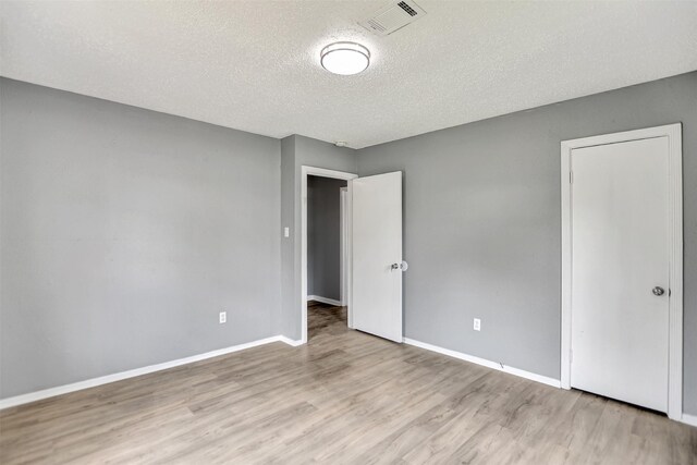 spare room featuring a textured ceiling and hardwood / wood-style flooring