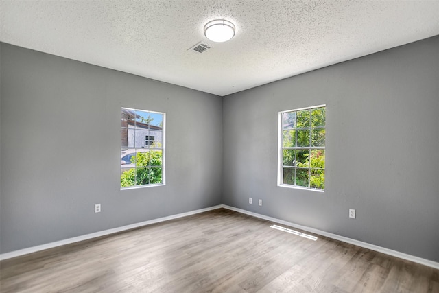 unfurnished room featuring hardwood / wood-style flooring, plenty of natural light, and a textured ceiling