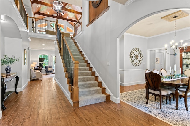 dining space featuring a notable chandelier, light hardwood / wood-style floors, beamed ceiling, ornamental molding, and a high ceiling