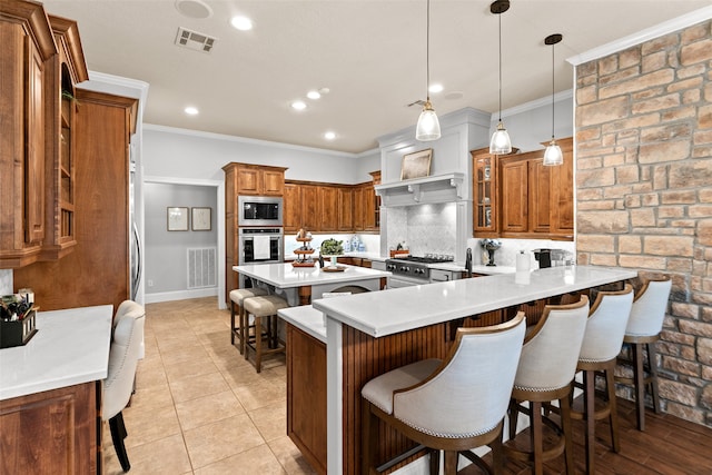 kitchen with a breakfast bar area, pendant lighting, appliances with stainless steel finishes, decorative backsplash, and kitchen peninsula