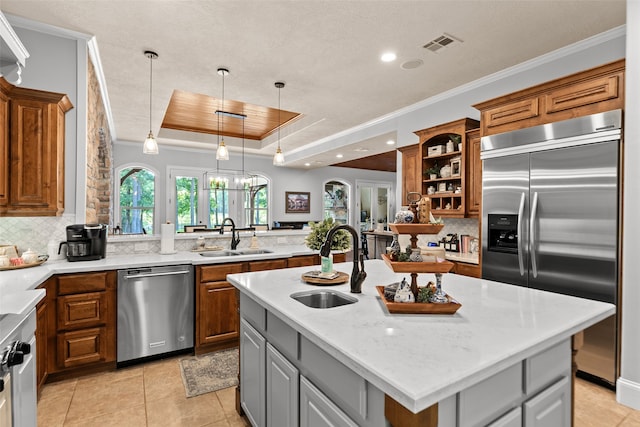 kitchen with a center island with sink, decorative backsplash, a raised ceiling, and stainless steel appliances