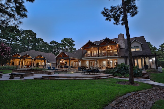 back house at dusk with a lawn and a patio area