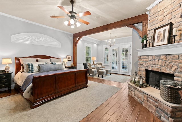 bedroom with crown molding, light wood-type flooring, a fireplace, and ceiling fan with notable chandelier