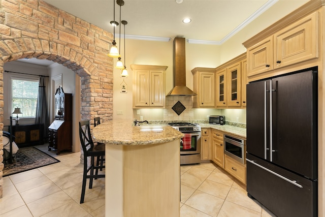 kitchen featuring kitchen peninsula, crown molding, wall chimney exhaust hood, a kitchen breakfast bar, and stainless steel appliances