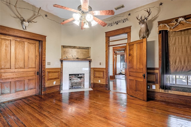 unfurnished living room featuring ceiling fan, a fireplace, and wood-type flooring