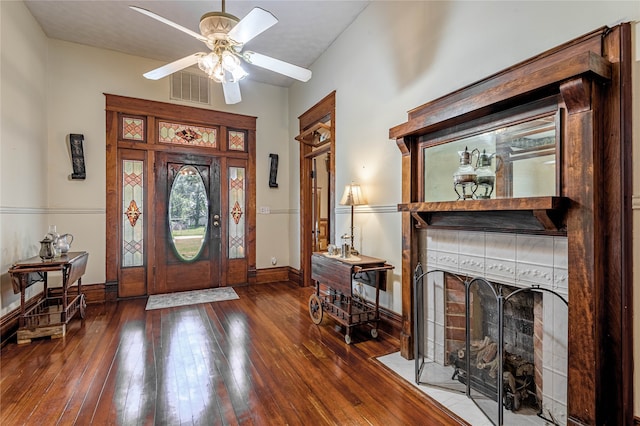 entrance foyer with ceiling fan, a tile fireplace, and hardwood / wood-style flooring