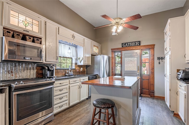 kitchen with stainless steel appliances, dark hardwood / wood-style flooring, ceiling fan, backsplash, and a center island