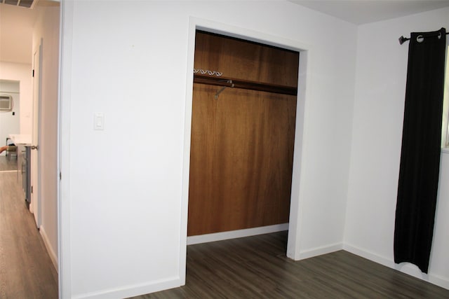 unfurnished bedroom with an AC wall unit, a closet, and dark hardwood / wood-style floors