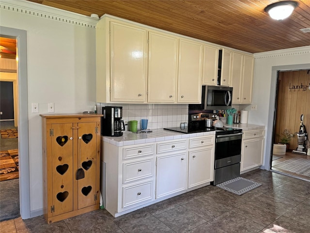 kitchen with decorative backsplash, stainless steel appliances, tile countertops, wooden ceiling, and white cabinets