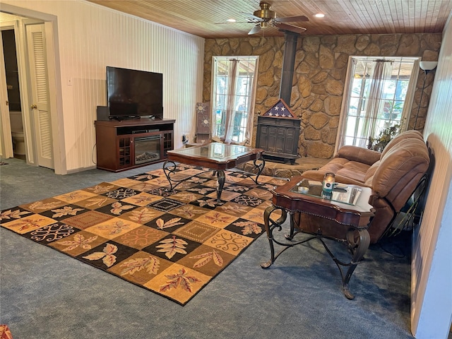 living room featuring carpet, plenty of natural light, a wood stove, and wooden ceiling