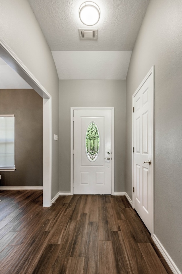 foyer entrance with a textured ceiling, lofted ceiling, and hardwood / wood-style flooring