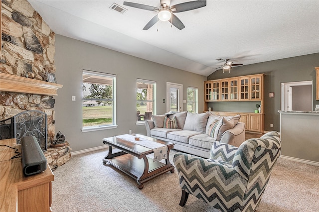 living room featuring a fireplace, a textured ceiling, lofted ceiling, ceiling fan, and light colored carpet