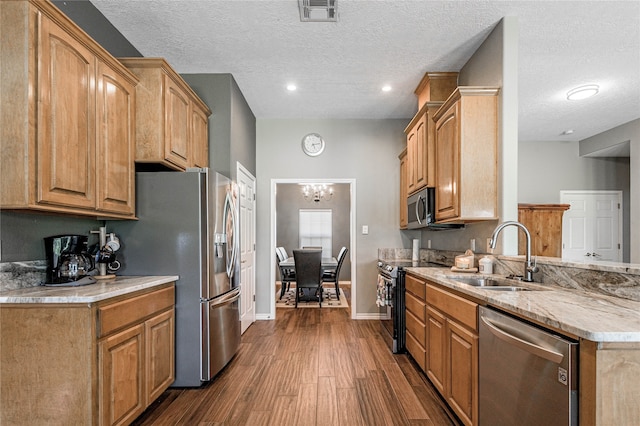 kitchen with appliances with stainless steel finishes, a textured ceiling, dark hardwood / wood-style floors, and sink