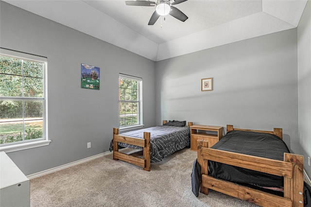 carpeted bedroom with ceiling fan and a tray ceiling