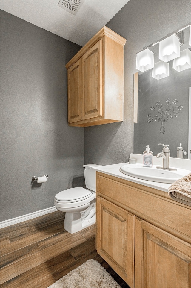 bathroom with vanity, toilet, and hardwood / wood-style floors