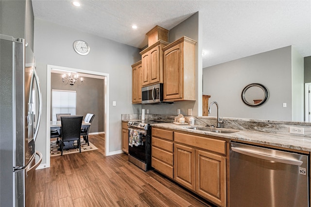 kitchen with a textured ceiling, stainless steel appliances, a chandelier, sink, and dark hardwood / wood-style floors