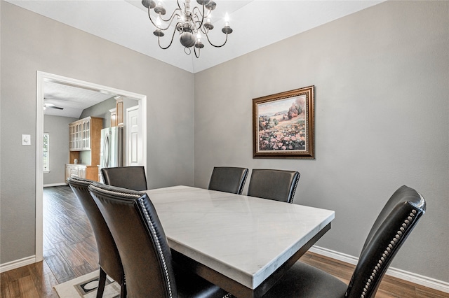 dining space with ceiling fan with notable chandelier and dark hardwood / wood-style floors