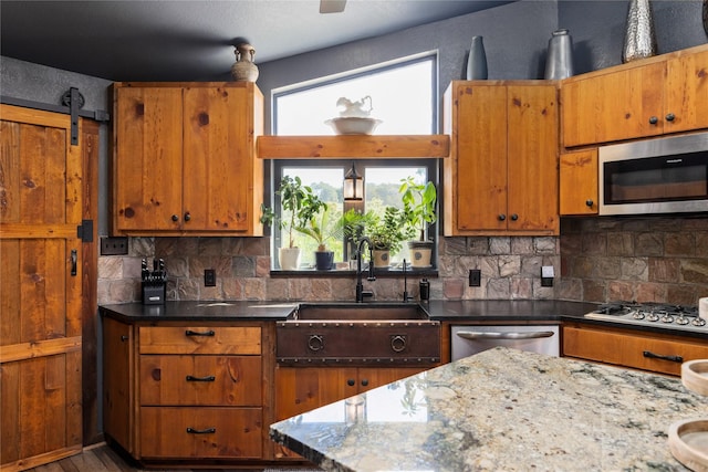 kitchen with tasteful backsplash, appliances with stainless steel finishes, sink, and dark stone counters