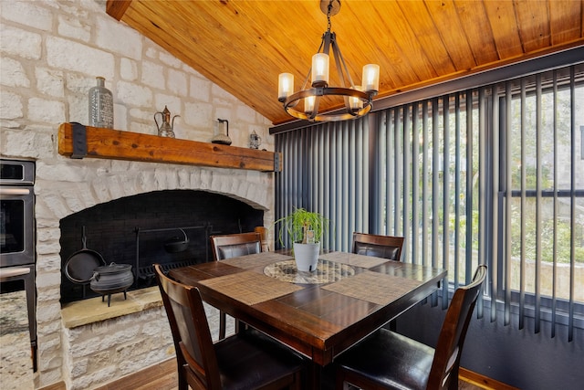 dining room with lofted ceiling, wood ceiling, hardwood / wood-style floors, an inviting chandelier, and a fireplace