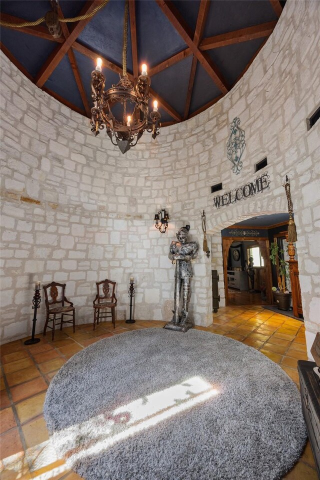 interior space with beamed ceiling, light tile patterned floors, high vaulted ceiling, and a chandelier