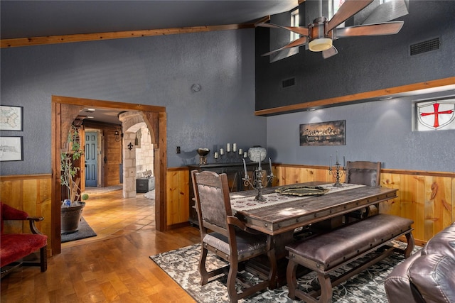 dining area featuring hardwood / wood-style flooring, ceiling fan, and wood walls