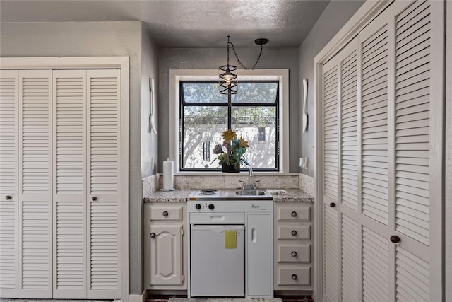 kitchen featuring hanging light fixtures, a textured ceiling, and white cabinets