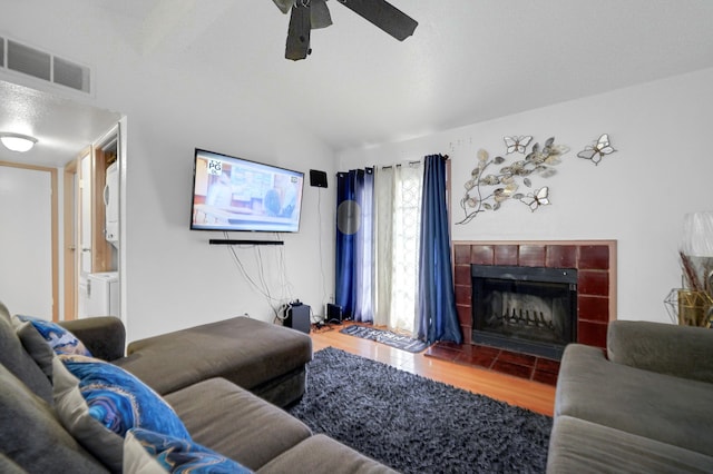 living room with ceiling fan, a tiled fireplace, a healthy amount of sunlight, and hardwood / wood-style floors