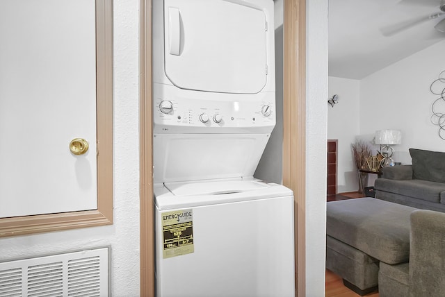 clothes washing area with hardwood / wood-style flooring and stacked washer and clothes dryer