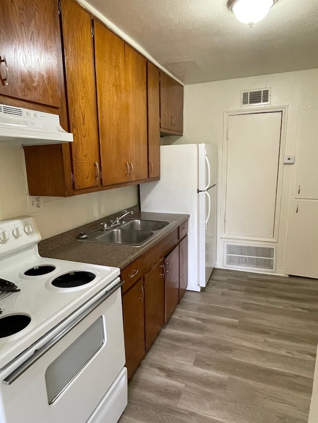 kitchen with white appliances, sink, a textured ceiling, and hardwood / wood-style flooring