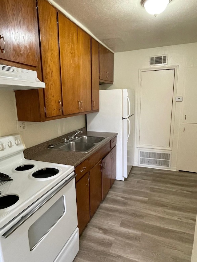 kitchen with white appliances, under cabinet range hood, visible vents, and a sink