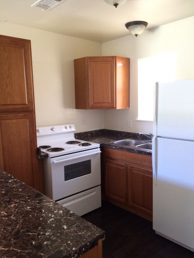 kitchen with white appliances, sink, and dark stone counters