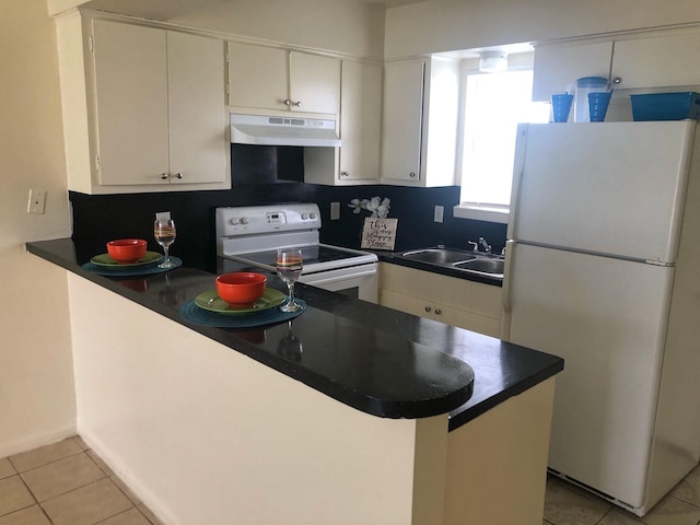 kitchen with white appliances, light tile patterned floors, a peninsula, under cabinet range hood, and a sink