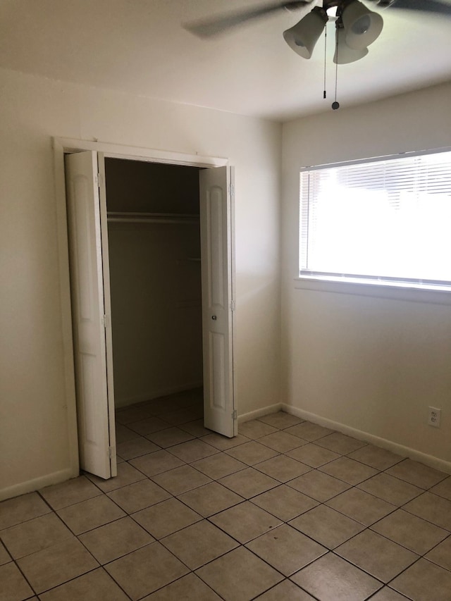 unfurnished bedroom with light tile patterned floors, a closet, and ceiling fan