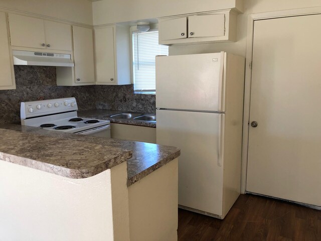 kitchen featuring kitchen peninsula, backsplash, dark wood-type flooring, and white appliances