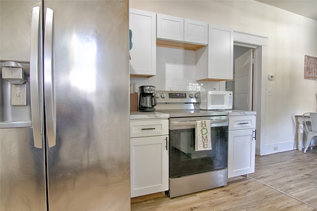 kitchen with appliances with stainless steel finishes, backsplash, light wood-type flooring, and white cabinetry