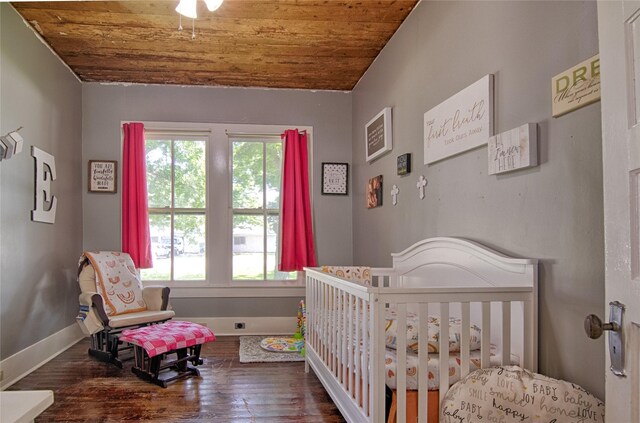 bedroom featuring hardwood / wood-style floors, a nursery area, and wooden ceiling