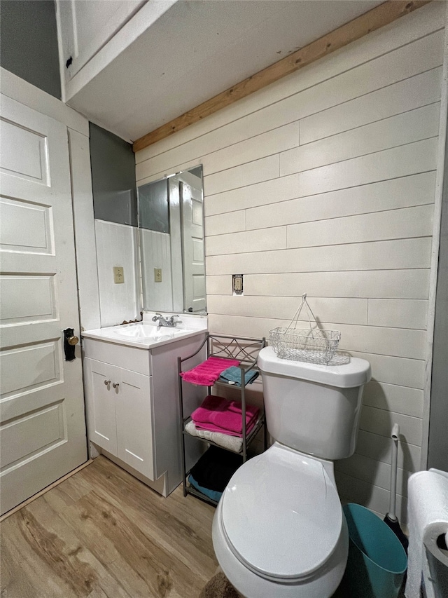 bathroom featuring wood walls, toilet, vanity, and wood-type flooring