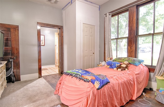 bedroom with ensuite bath and hardwood / wood-style floors