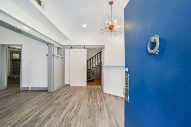 interior space with a barn door, an inviting chandelier, and light hardwood / wood-style flooring