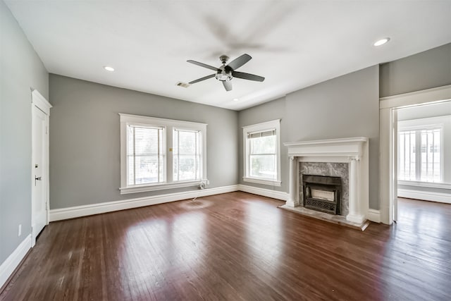 unfurnished living room with dark wood-type flooring, ceiling fan, and a high end fireplace