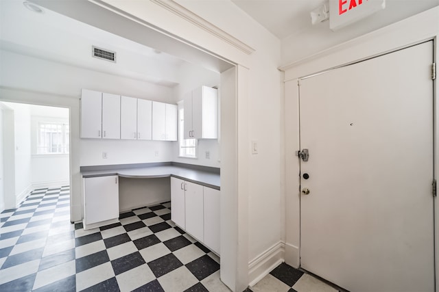 kitchen featuring built in desk, a wealth of natural light, and white cabinets