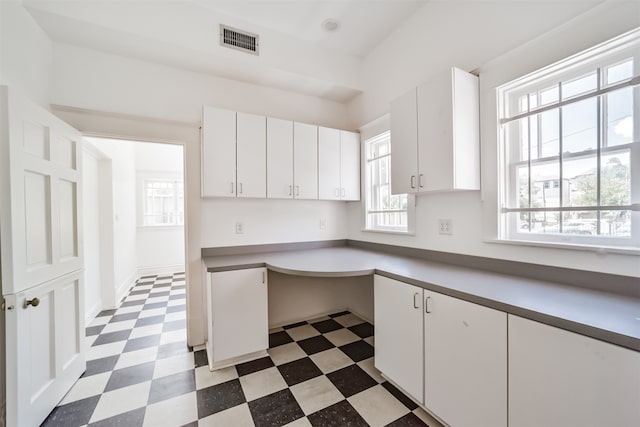 kitchen with white cabinets, built in desk, and plenty of natural light